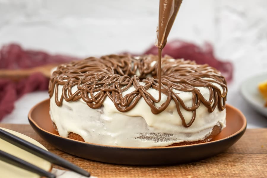 Bolo toalha felpuda com cobertura branca e fios de chocolate